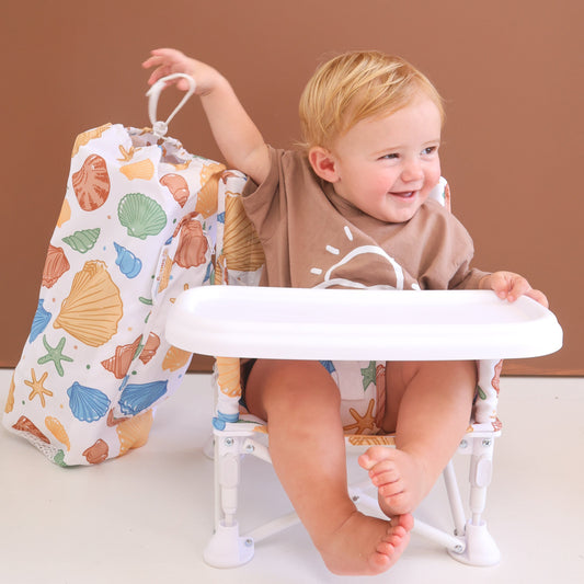 Child sitting on a white chair with a colorful bag next to them against a brown background