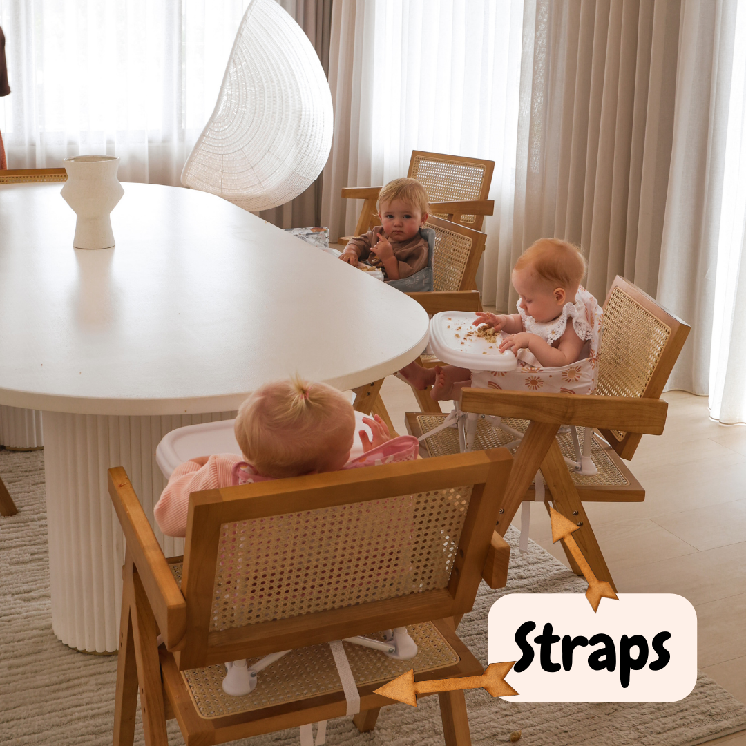 Three children sitting at a dining table with high chairs, featuring the brand 'Straps'.
